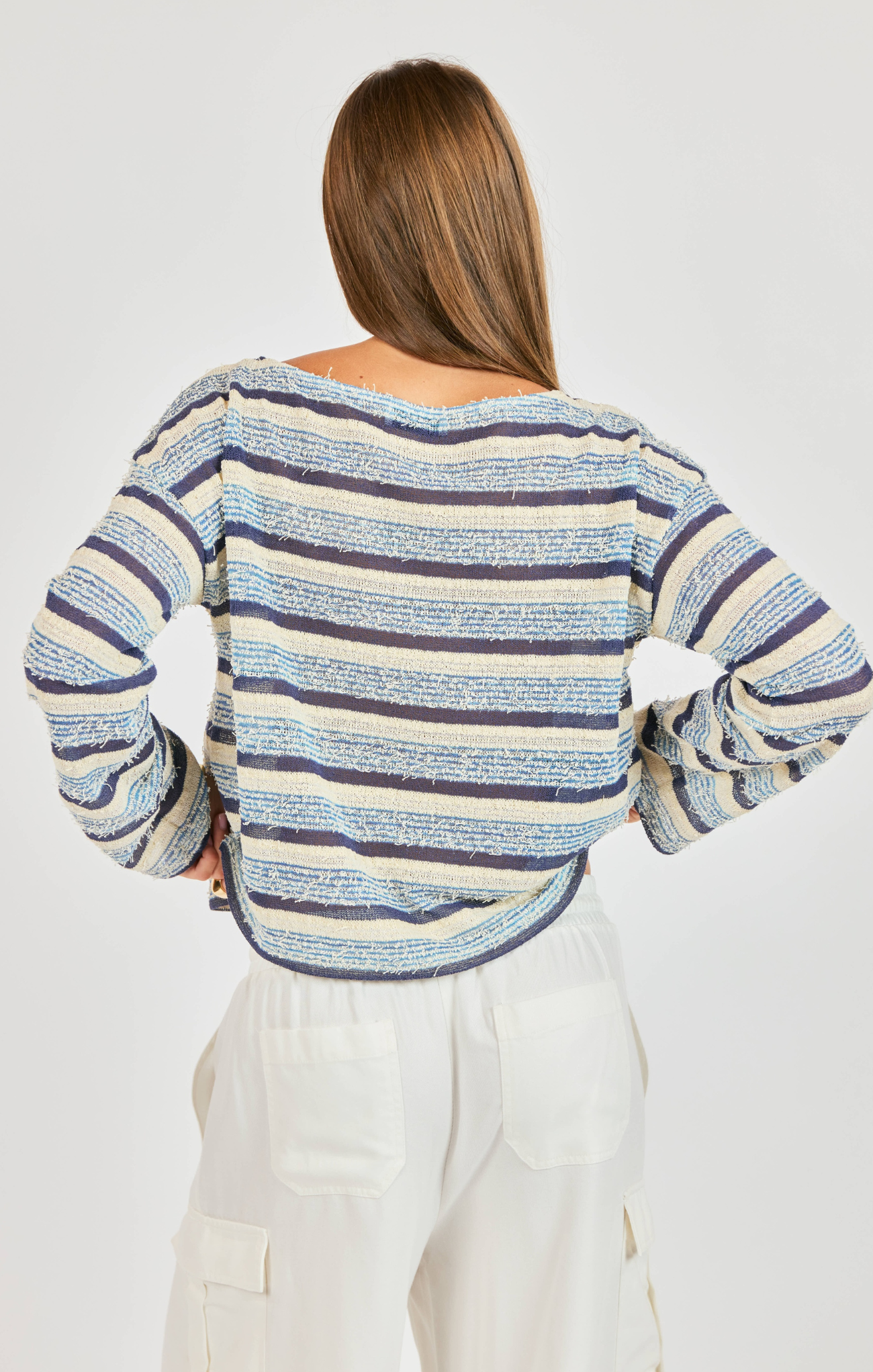 woman wearing striped blue shirt with white pants on white background