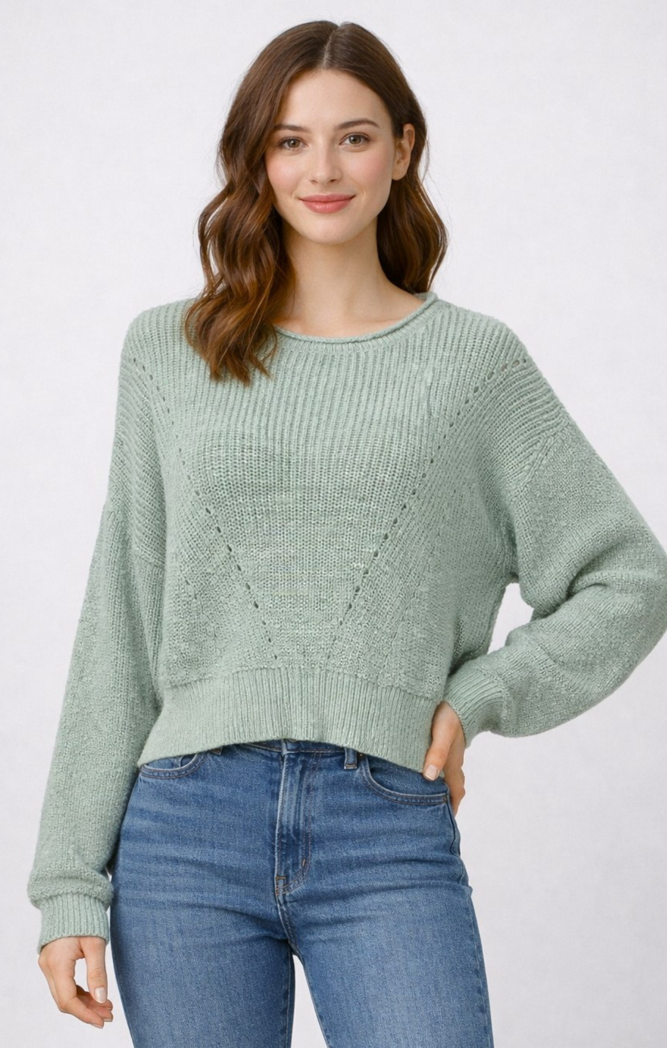 woman wearing sage green sweater with blue jeans on white background