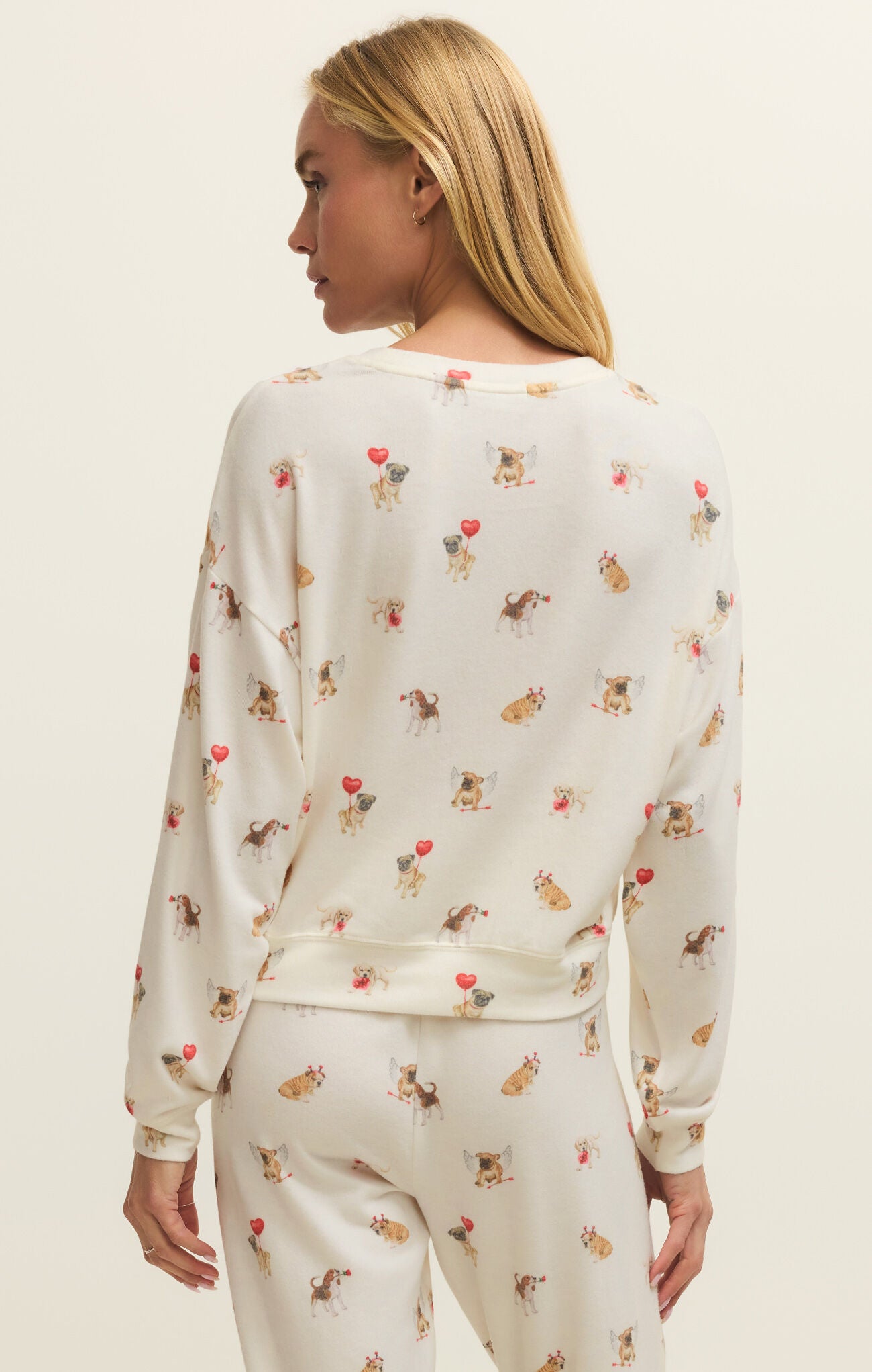 Woman wearing a cream-colored long-sleeve top with animal print on a plain background