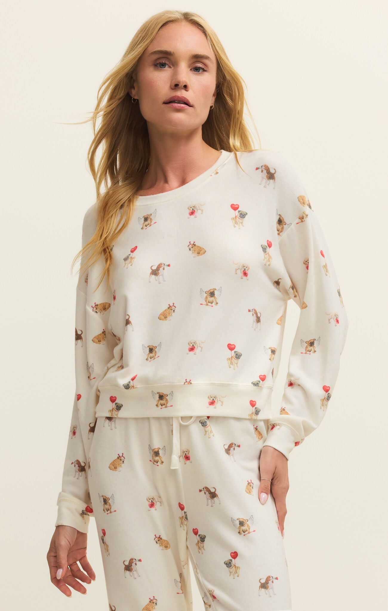 Woman wearing a cream-colored pajama set with animal prints on a plain background