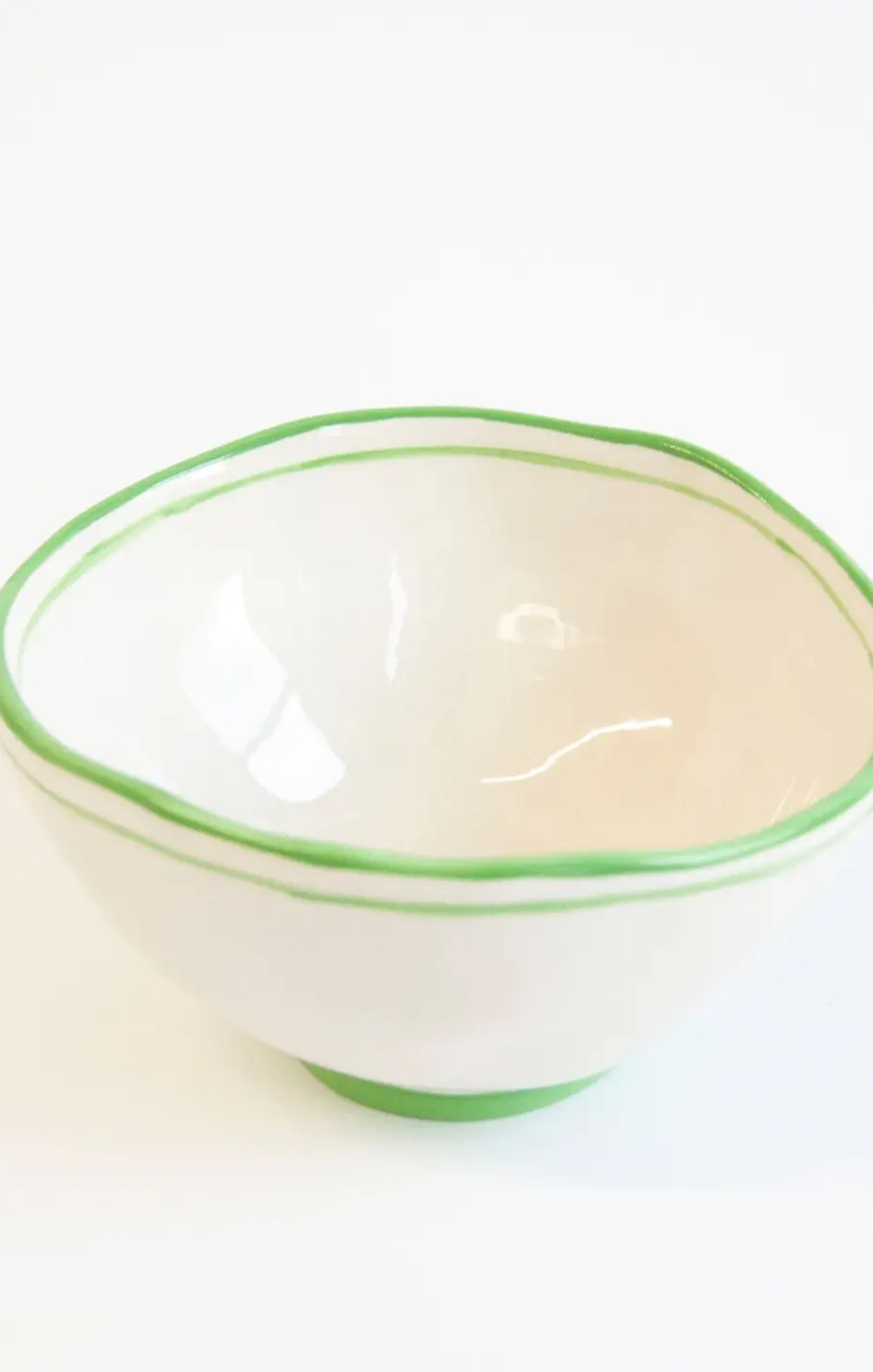 White bowl with green rim on a white background
