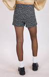 Person wearing black and white patterned shorts with a plain background