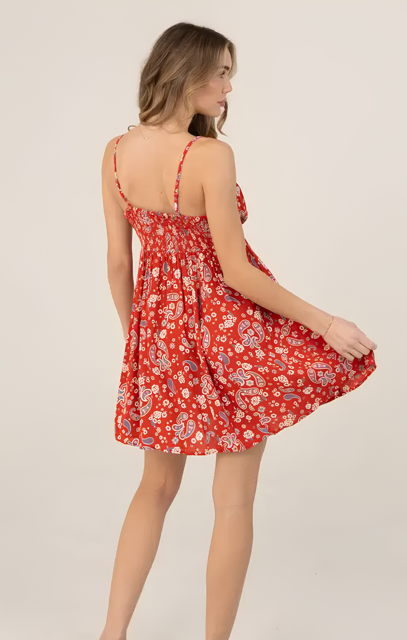 Woman wearing a red floral dress against a plain background