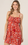 Woman wearing a red patterned dress against a plain background