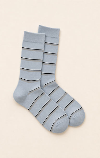 Gray striped sock on a white surface with a book in the background
