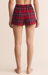 Red plaid shorts worn by a person on a beige background