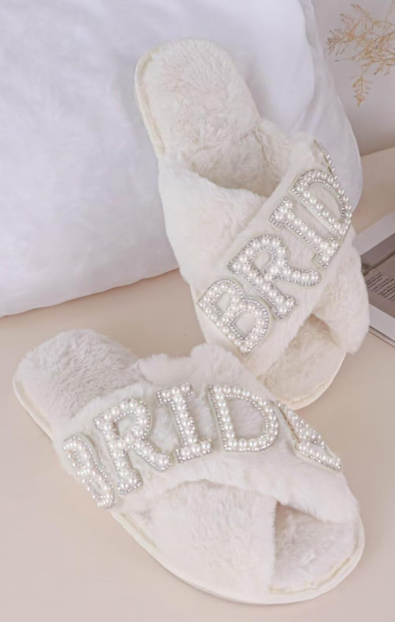 White slippers with rhinestone embellishments on a light background