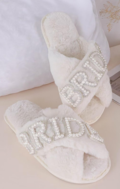 White slippers with rhinestone embellishments on a light background