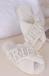 White slippers with rhinestone embellishments on a light background