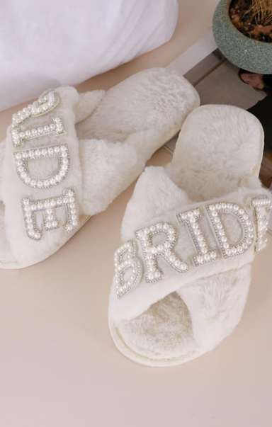 White slippers with 'Bride' and 'Groom' text in rhinestones on a light background