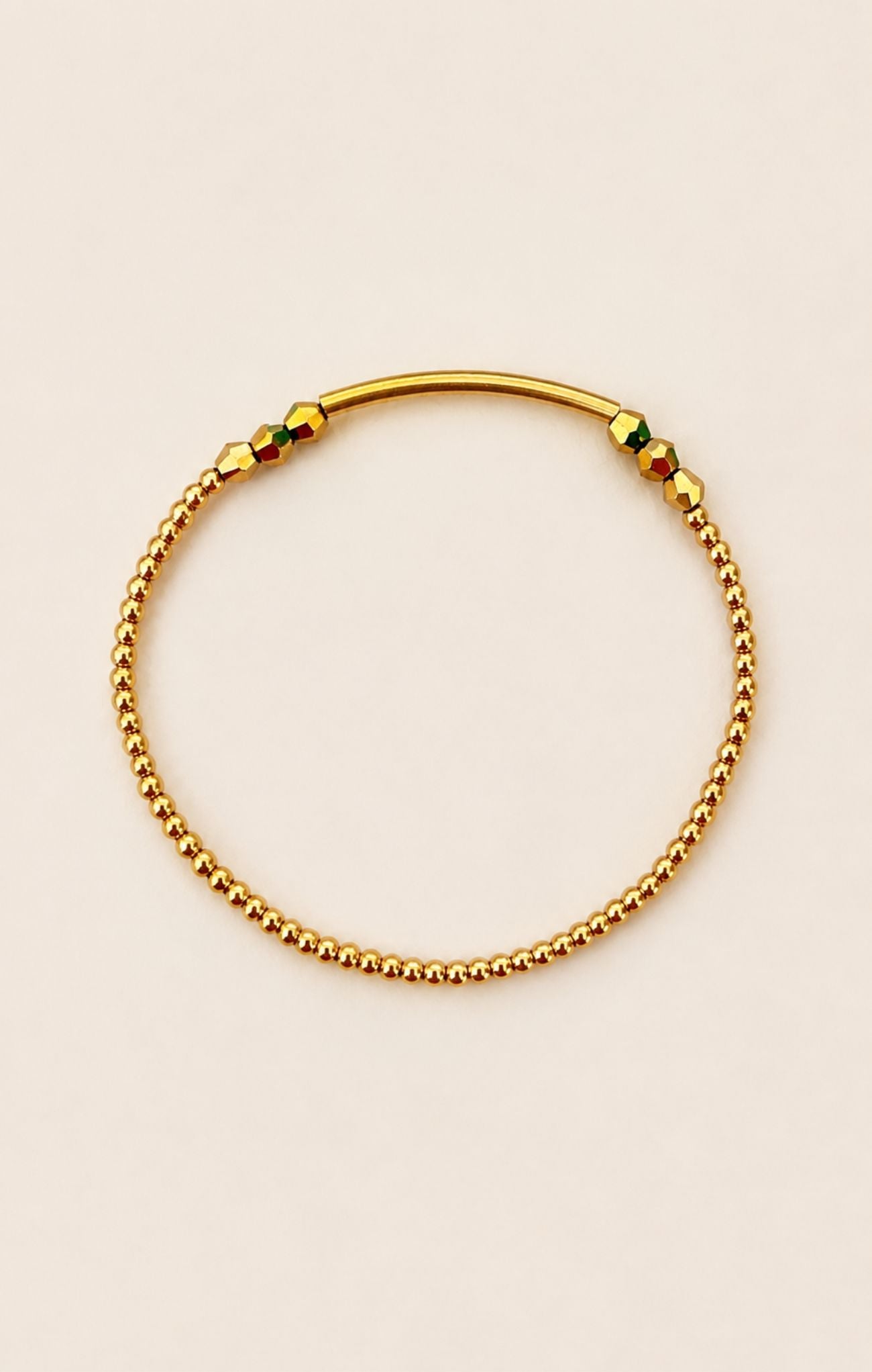 Gold beaded bracelet on a beige background