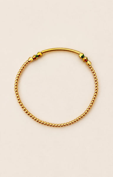 Gold beaded bracelet on a beige background