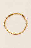 Gold beaded bracelet on a beige background
