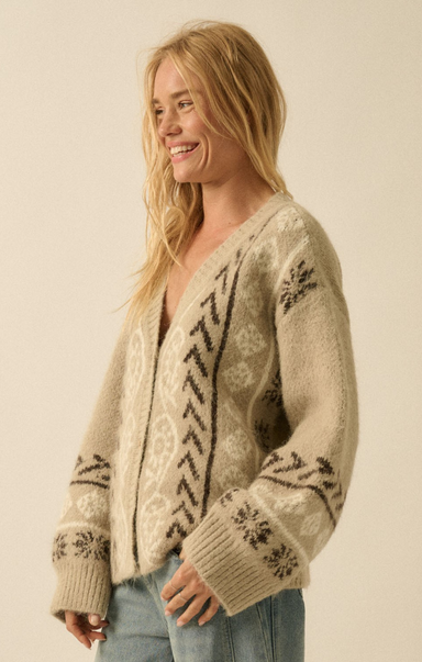 Woman wearing a patterned beige sweater against a plain background