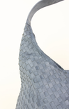 Close-up of a textured blue handbag with a white background
