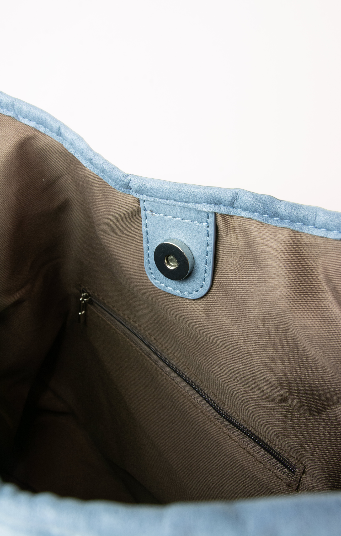 Close-up of a brown bag with a blue interior and zipper, on a light gray background.
