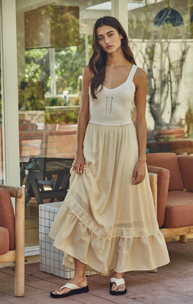 Woman wearing a white top and beige skirt in an outdoor setting