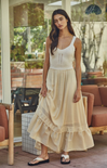 Woman wearing a white top and beige skirt in an outdoor setting