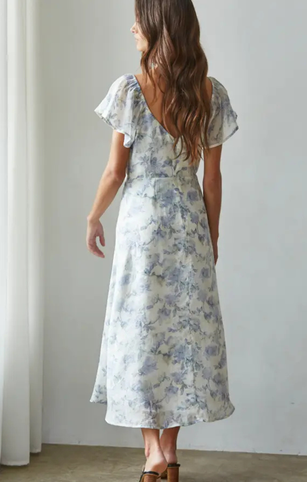 Woman wearing a floral dress against a plain background