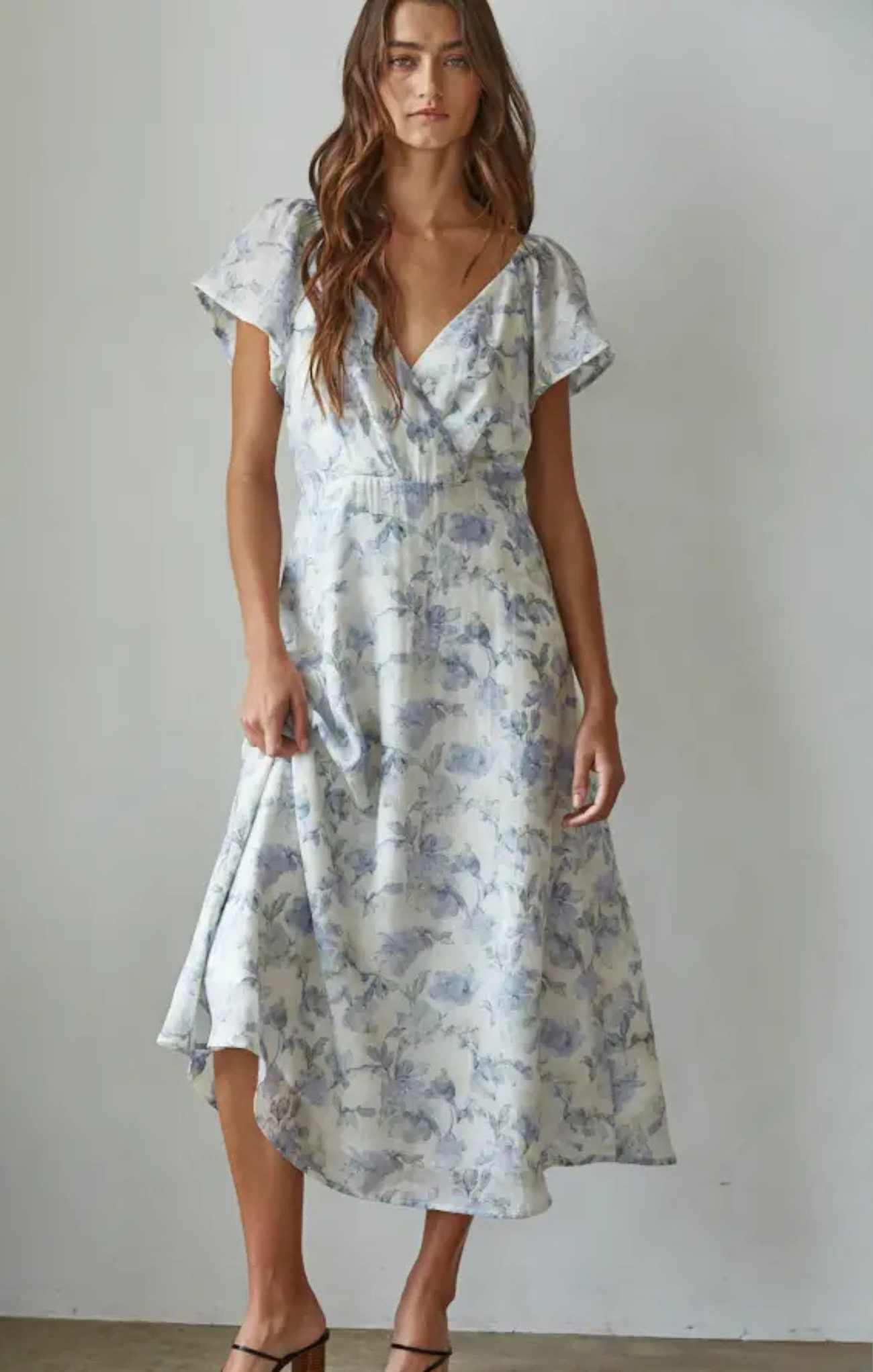 Woman wearing a floral dress against a plain background