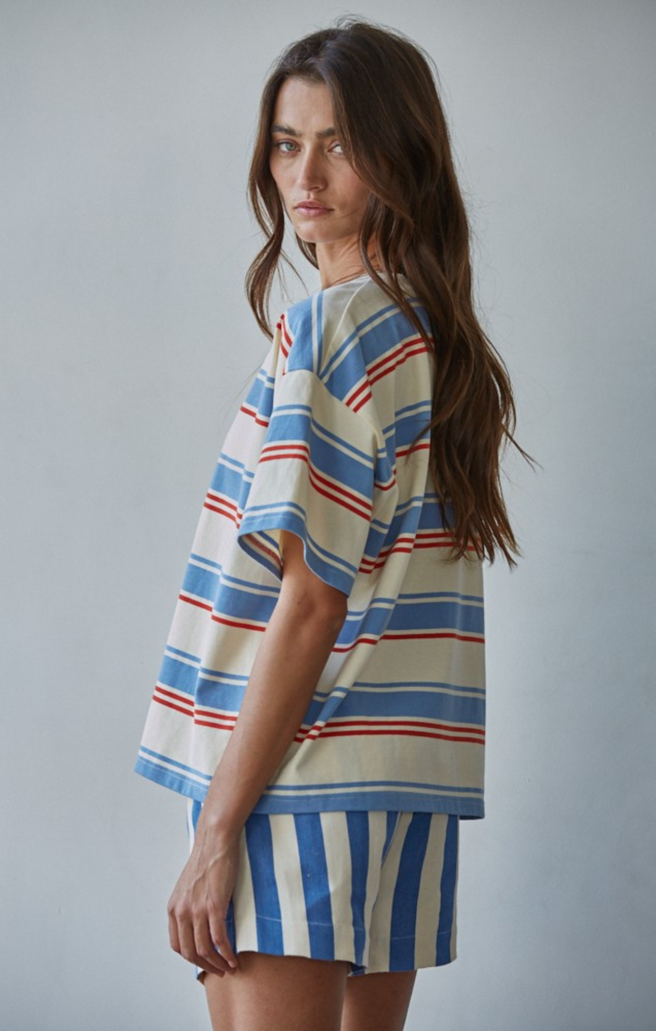 Woman wearing a striped outfit with a plain background