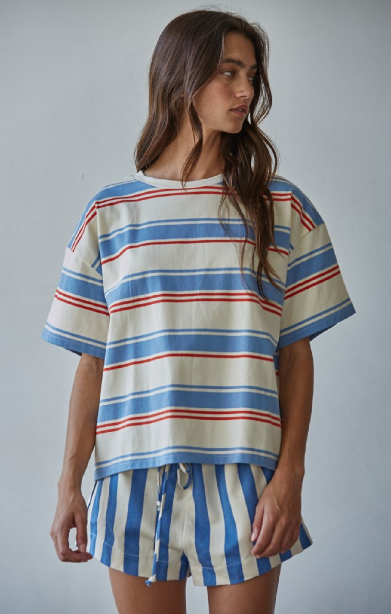 Woman wearing a striped shirt and shorts set against a plain background