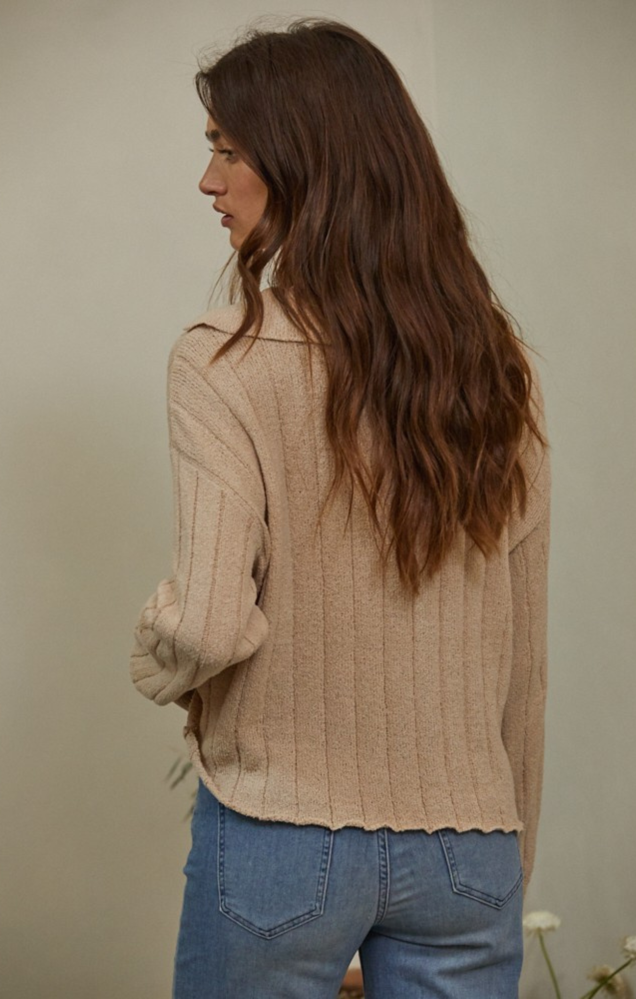 women in beige sweater and blue jeans with neutral background