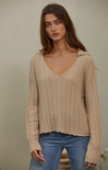 women in beige sweater and blue jeans with neutral background