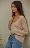 women in beige sweater and blue jeans with neutral background