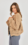 Woman wearing a beige knitted sweater on a plain background