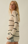 Woman wearing a cream sweater with black stripes against a plain background