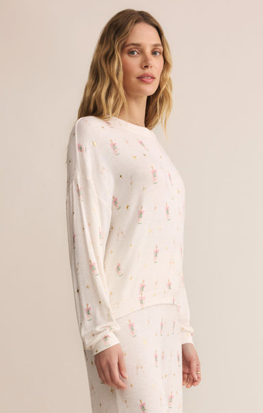 Woman wearing a white long-sleeve top with a subtle pattern on a beige background