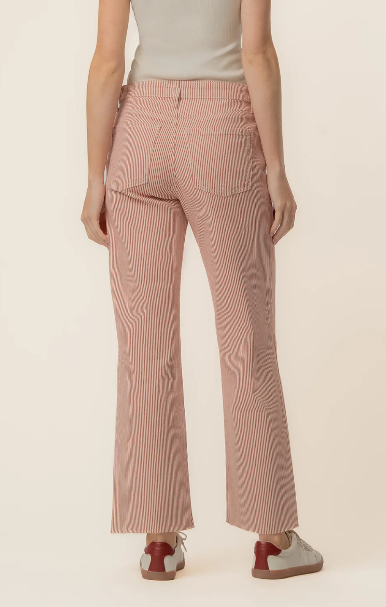Person wearing pink ribbed pants on a beige background