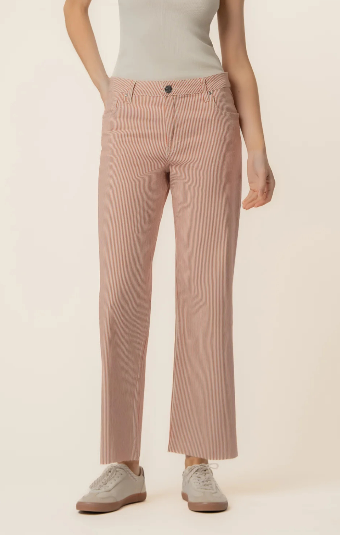 Person wearing light pink pants and a white top on a beige background