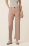 Person wearing light pink pants and a white top on a beige background