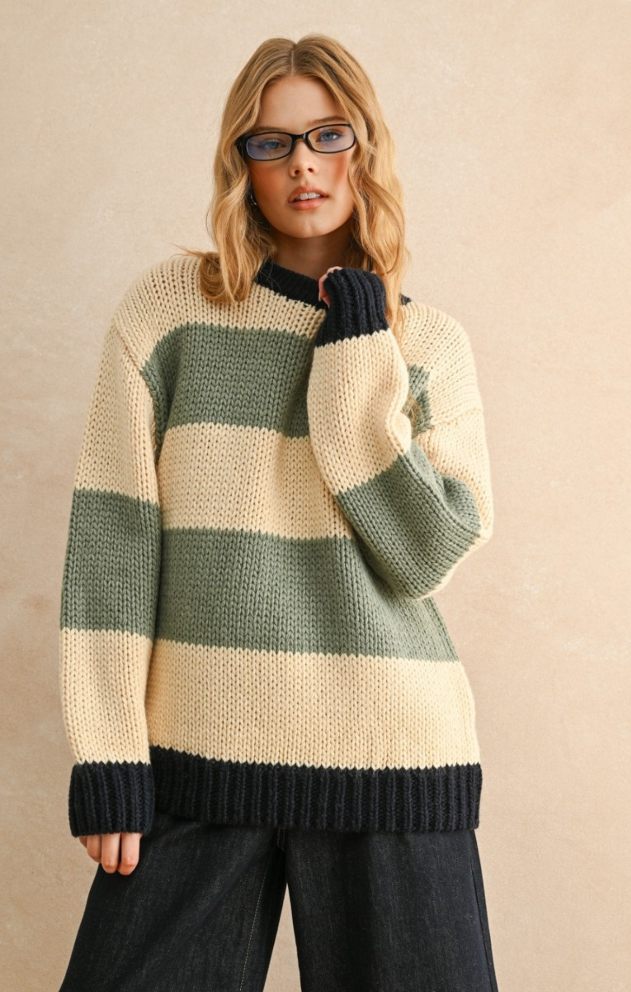 Woman wearing a striped sweater with green and beige colors on a beige background