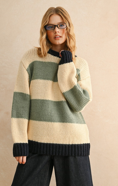 Woman wearing a striped sweater with green and beige colors on a beige background
