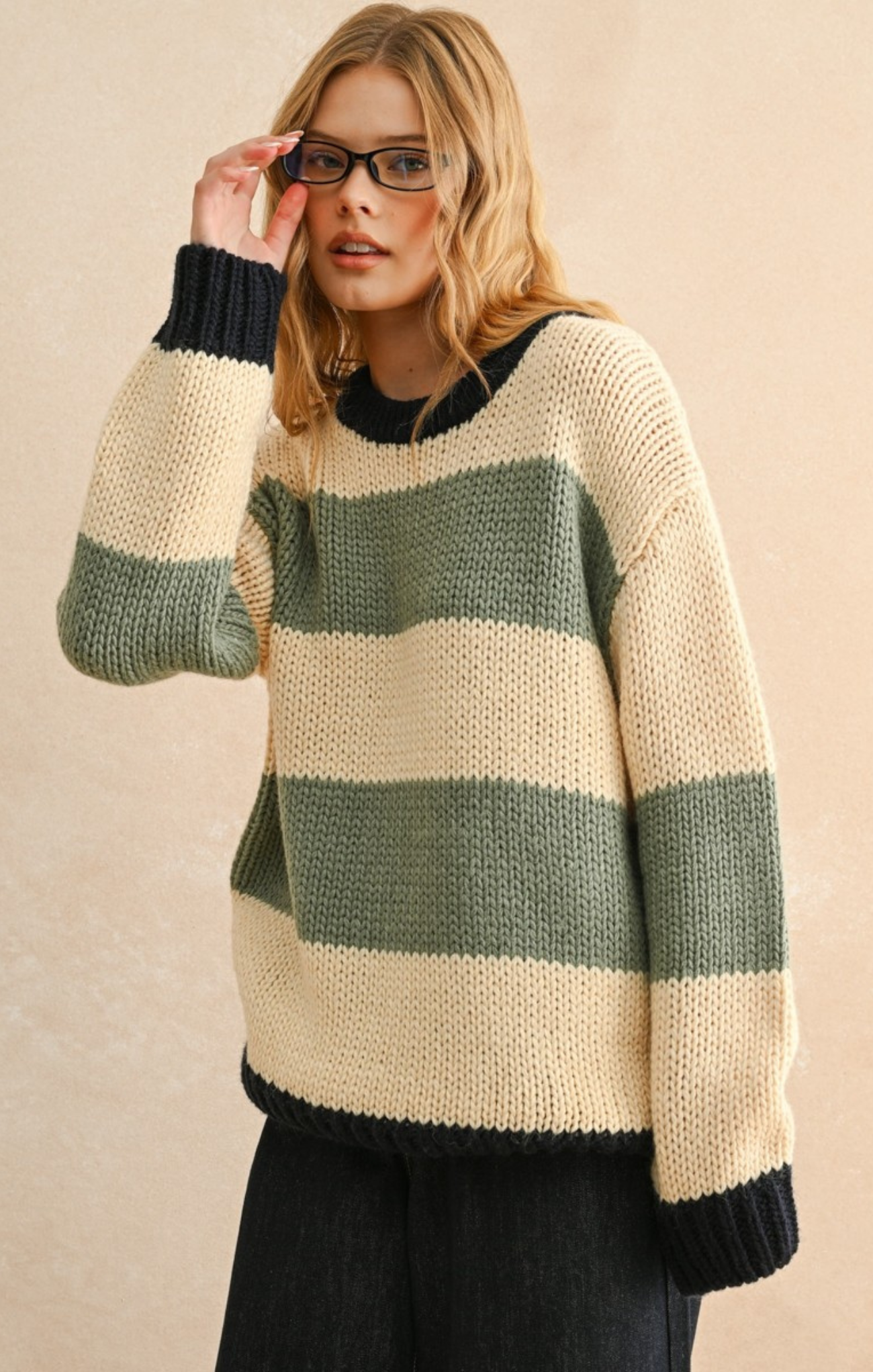 Woman wearing a striped sweater with green and beige colors on a beige background