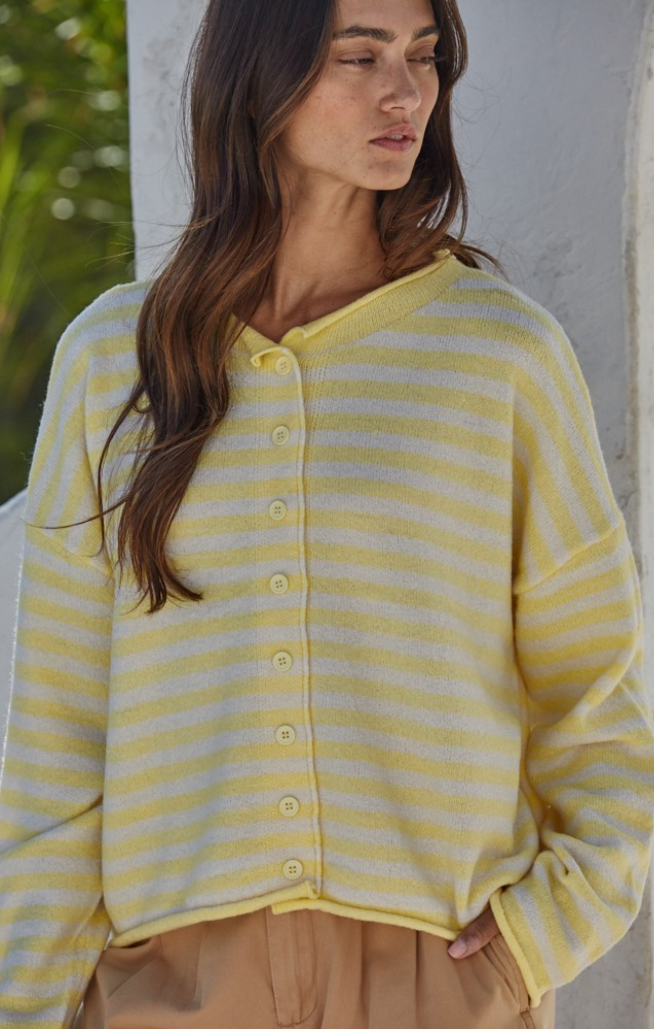 Woman wearing a yellow and white striped cardigan against a neutral background