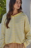 Woman wearing a yellow and white striped cardigan against a neutral background
