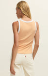 Woman wearing a peach tank top with white trim on a plain background