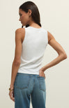 Woman wearing a white sleeveless top and blue jeans on a plain background