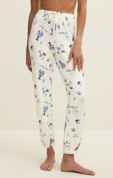 White pajama pants with blue pattern worn by a person on a beige background