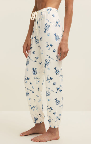 White pajama pants with blue animal print worn by a person on a beige background