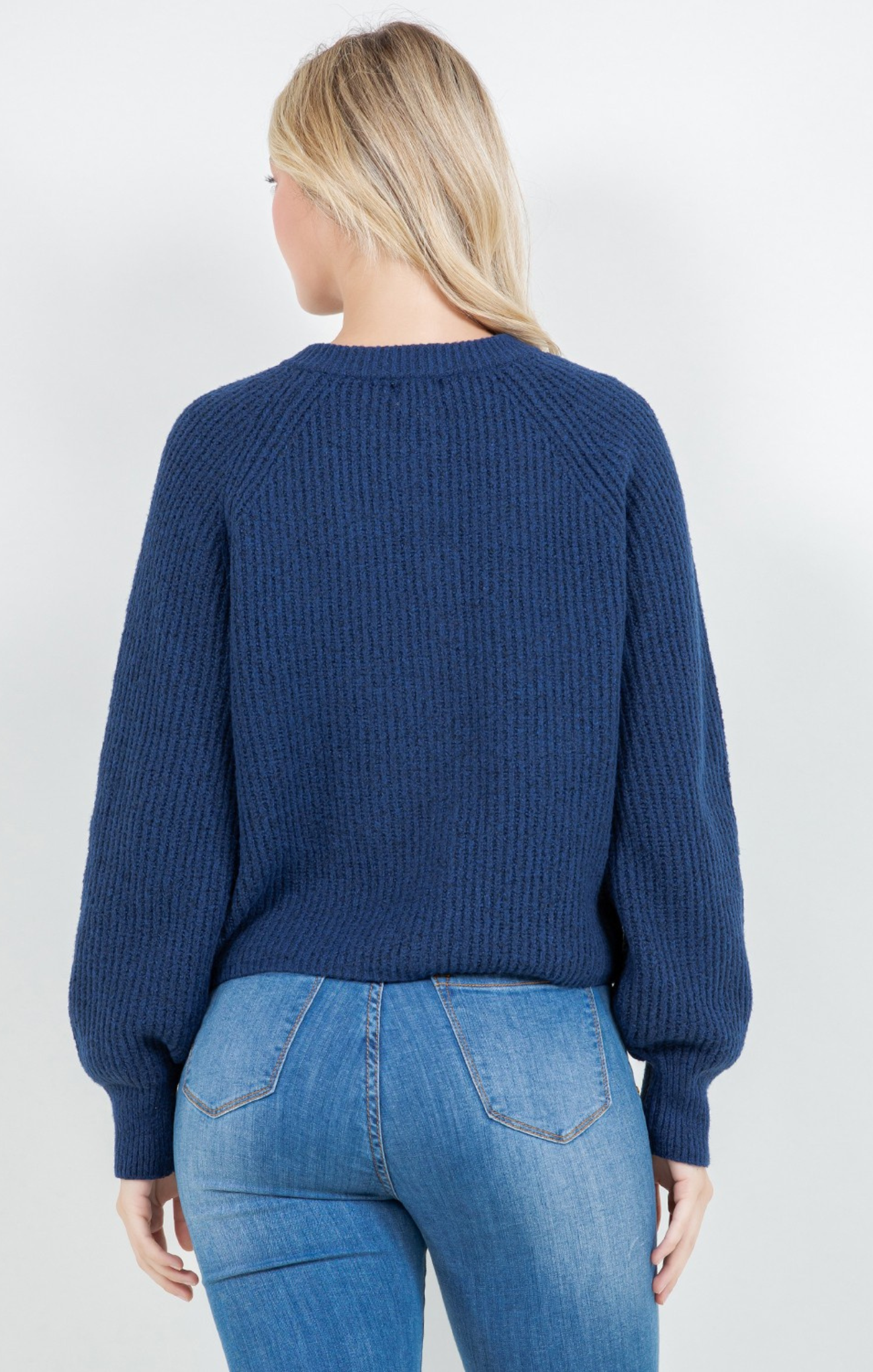 Person wearing a blue sweater and jeans on a white background