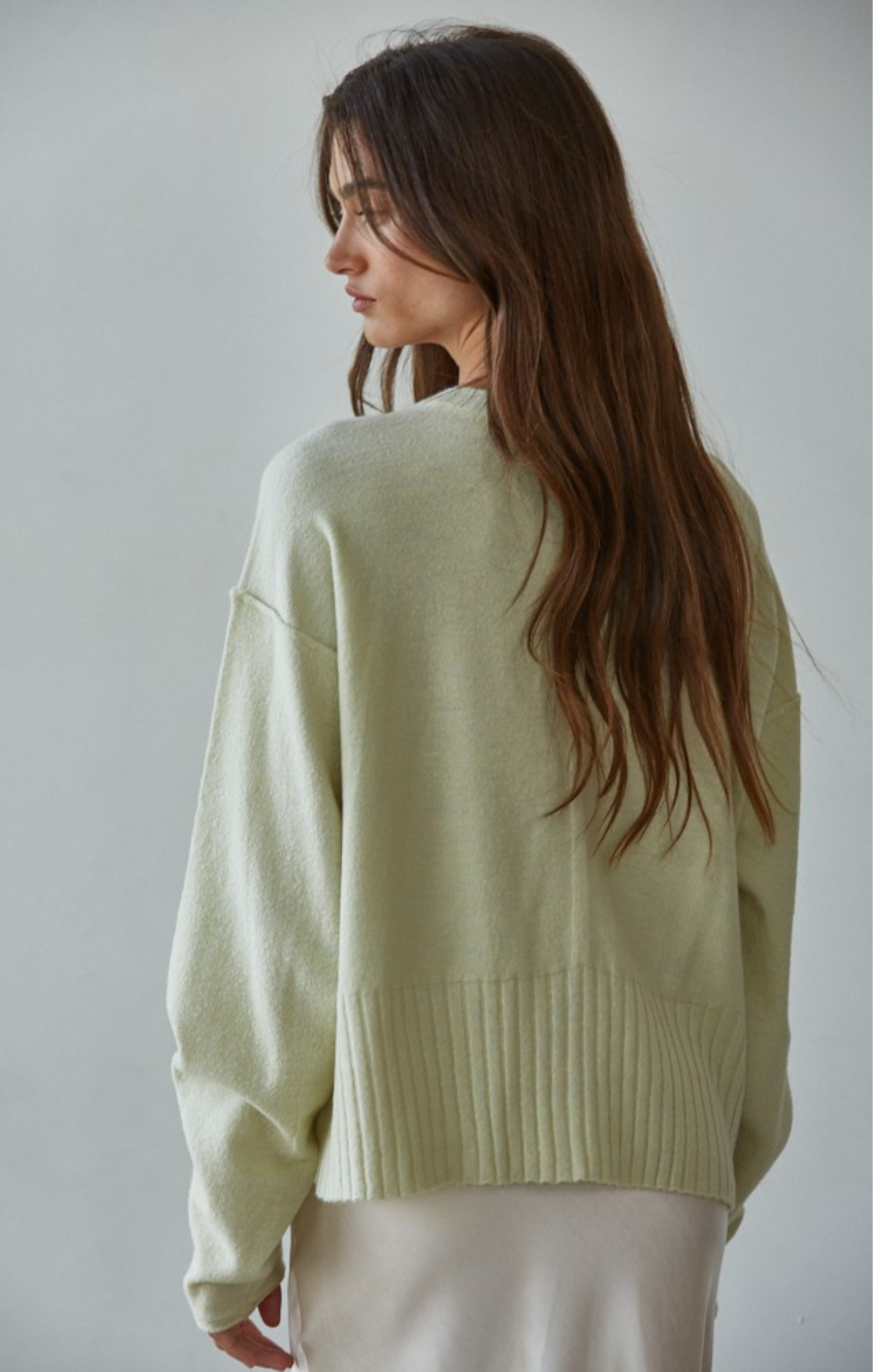 Woman wearing a light green sweater against a plain background