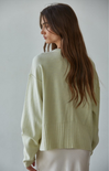 Woman wearing a light green sweater against a plain background