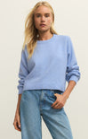 Woman wearing a light blue sweater and jeans against a plain background