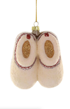 Decorative glass ornament shaped like a pair of ballet slippers with gold glitter on a white background.