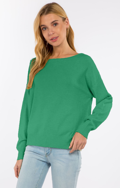 Woman wearing a green sweater and light blue jeans on a white background
